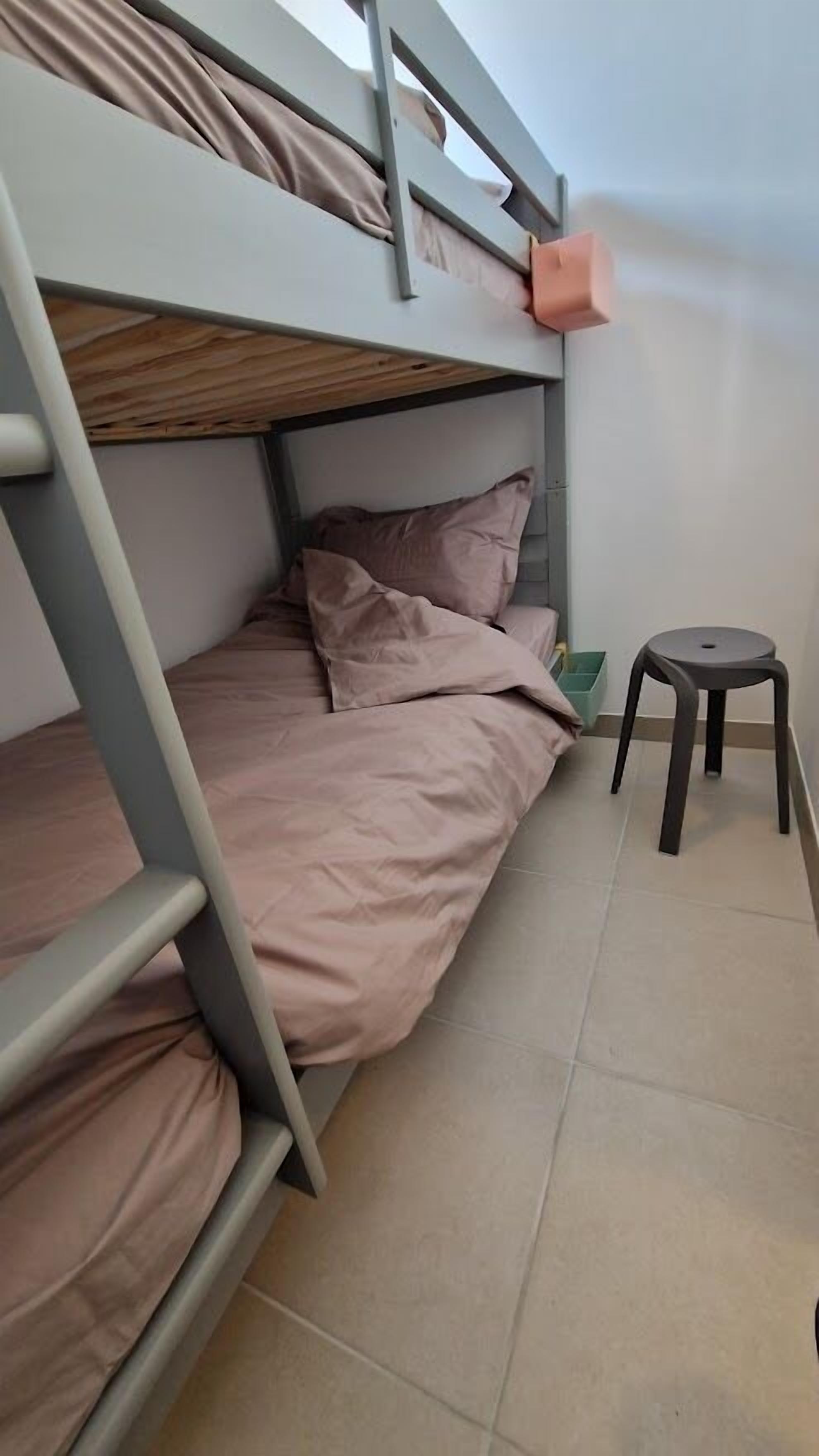 A bunk bed with a small stool beside it.