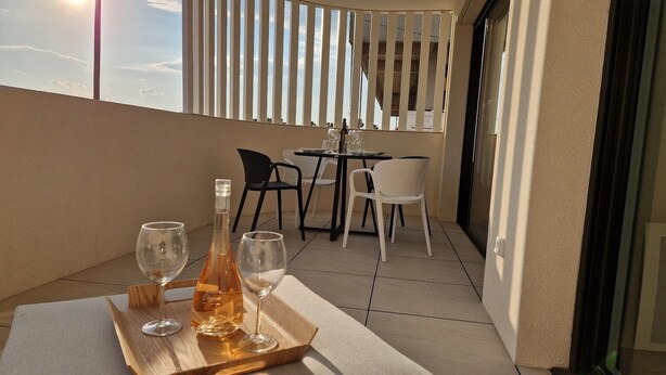En balkon med et bord dækket til to personer, inklusiv en flaske og to glas.