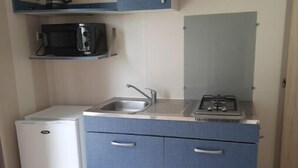 A compact kitchenette with a microwave, sink, and small refrigerator. - Mobil-home C007 (Boofzheim)