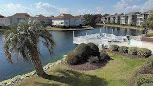 A waterfront property with a dock, a small bridge, and a well-maintained lawn.