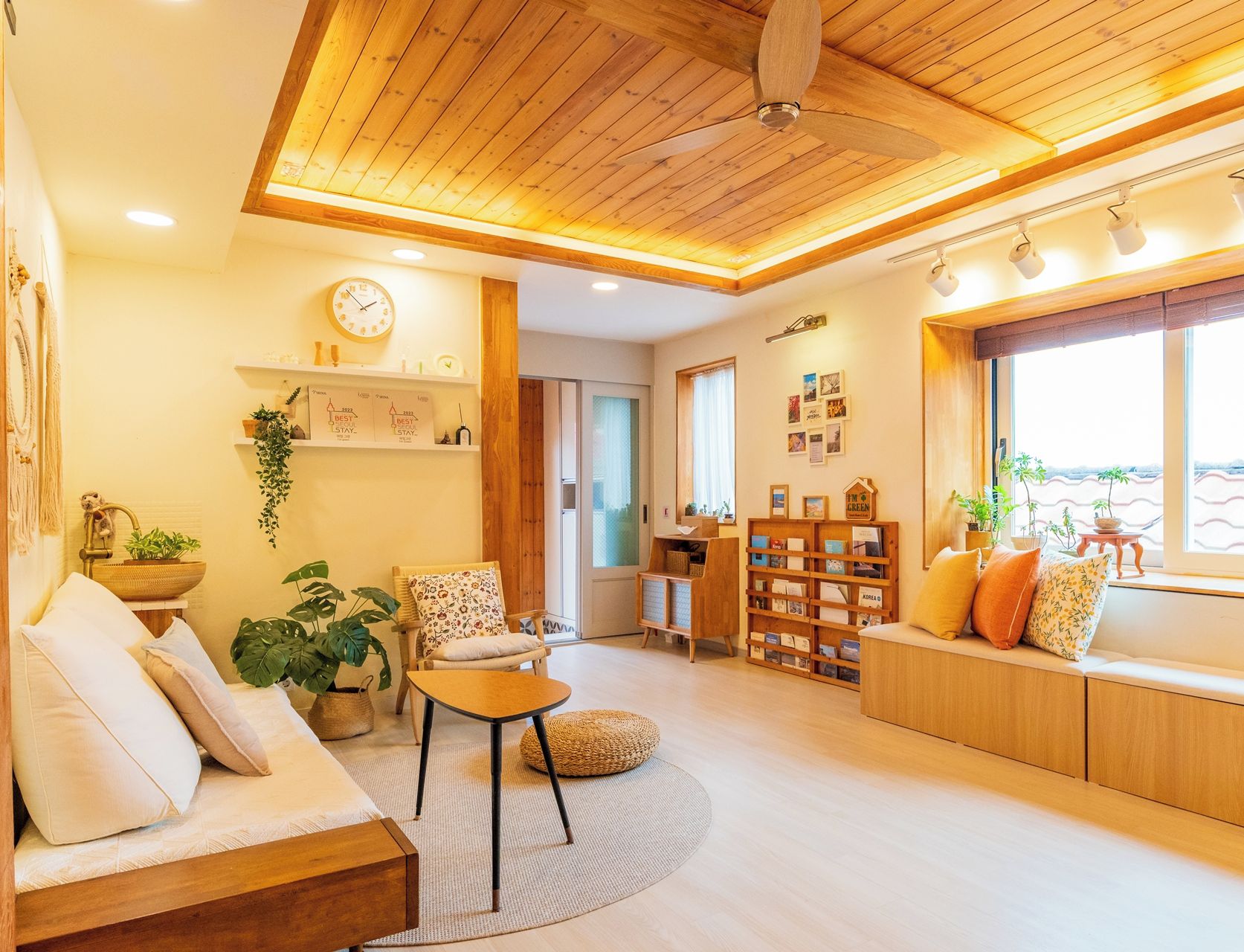 A cozy living room with a wooden ceiling, a sofa, a small table, and a bookshelf.