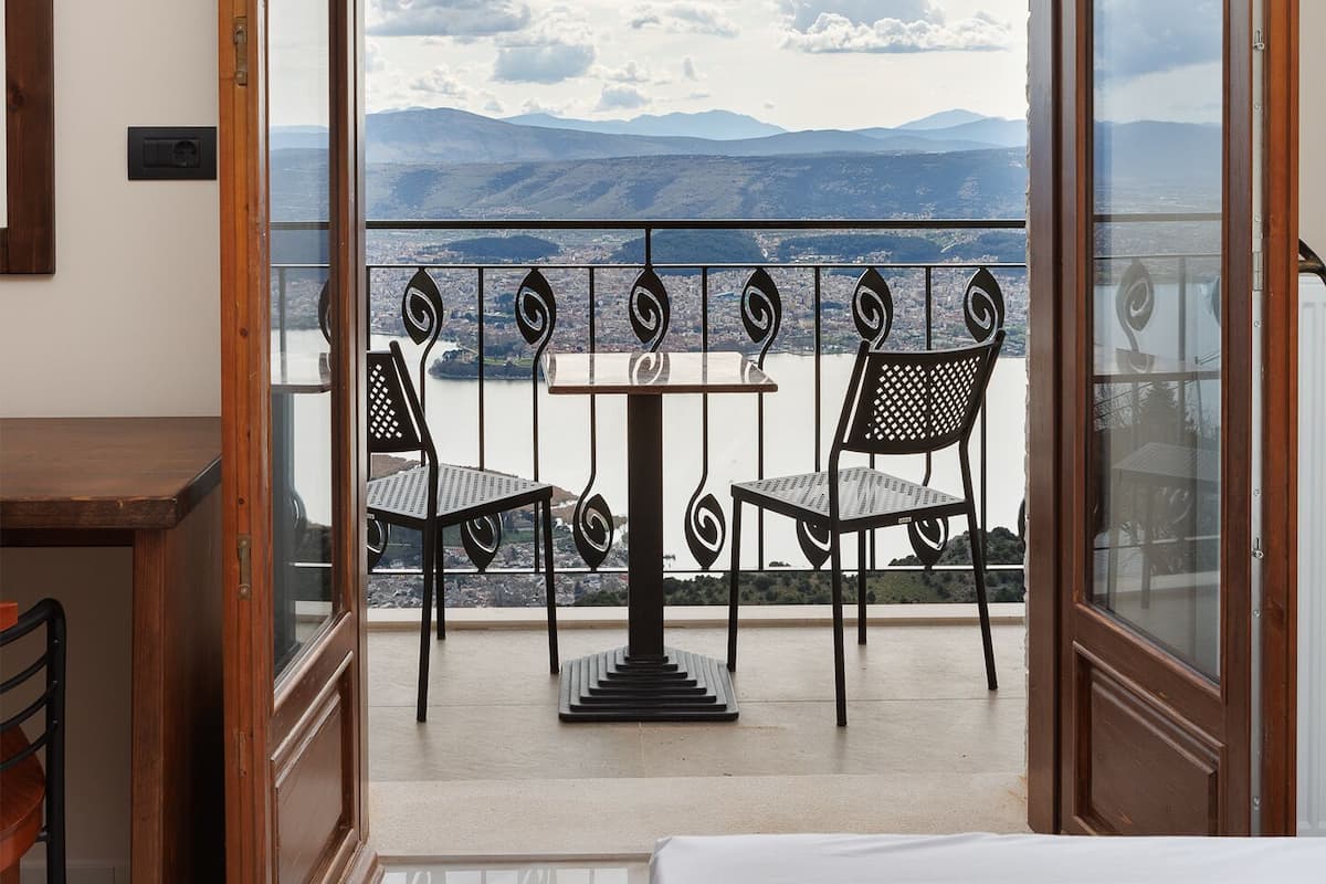 A balcony with a table and chairs, a wooden ceiling, and a view of mountains.
