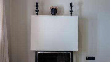 Una sala de estar moderna con chimenea, un televisor de pantalla plana montado encima y un diseño minimalista.