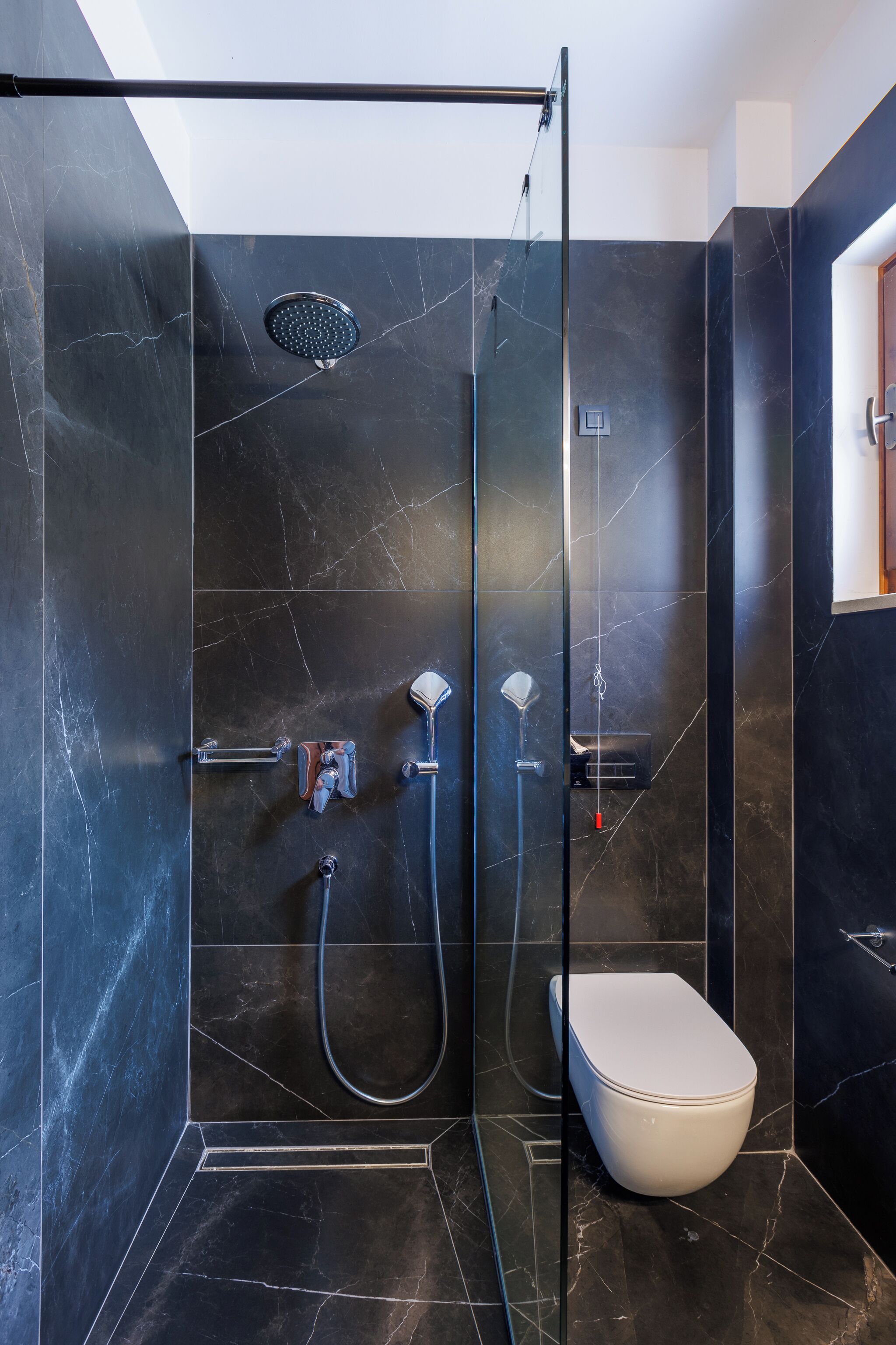 Een moderne badkamer met een glazen douchecabine, een toilet en een handdoekrek.