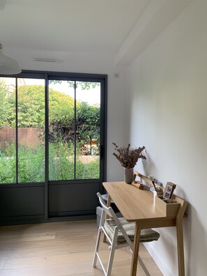 Relax in this serene space with a sliding glass door leading to an outdoor area, a dining table, and a comfortable chair.