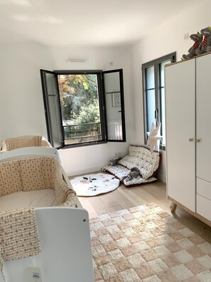 Relax in a cozy corner seating area with a sofa and cushion, featuring a storage cabinet and a window with a view of the surrounding trees.