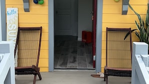 A porch with two wooden chairs, a small table, and a bag on the floor.