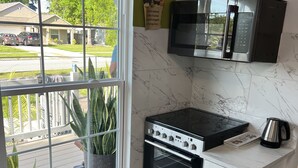 A kitchen with a built-in oven, microwave, and a window with a view of a residential street.