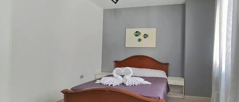 A bedroom with a wooden bed, a small bedside table, and a wall-mounted artwork.
