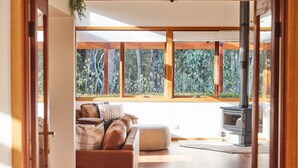 Un salon chaleureux avec un canapé, un pouf et un poêle à bois.