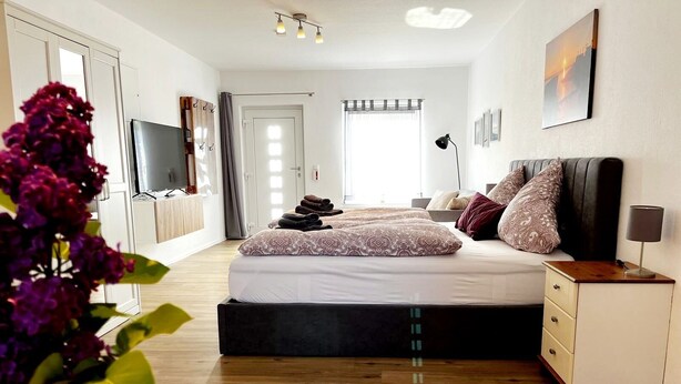 Une chambre moderne avec un grand lit, une table de chevet, une télévision et une armoire.