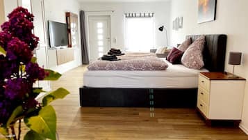 Ein modernes Schlafzimmer mit einem großen Bett, einem Nachttisch, einem Fernseher und einem Kleiderschrank.