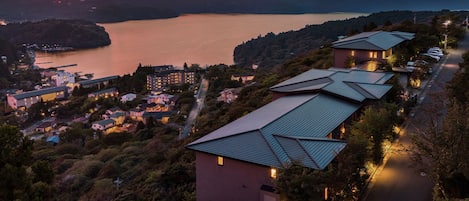A coastal hotel with multiple buildings, a road, and a view of the sea and hills.