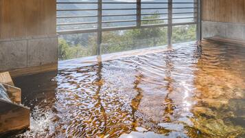 A hot spring bath with a view of a mountainous landscape through a window.