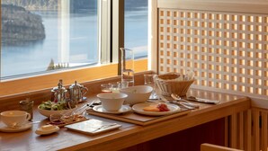 Una mesa de desayuno con vista a un lago y montañas a través de una ventana.