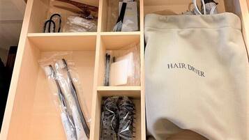 Une boîte de rangement compartimentée contenant des produits de soins capillaires et un sèche-cheveux.