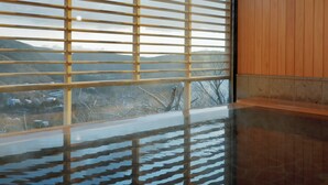 Habitación con un ventanal grande con persianas horizontales, pared de madera y suelo reflectante.