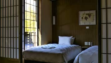 A traditional Japanese-style room with tatami flooring, a shoji screen door, and a bed with a white bedding.