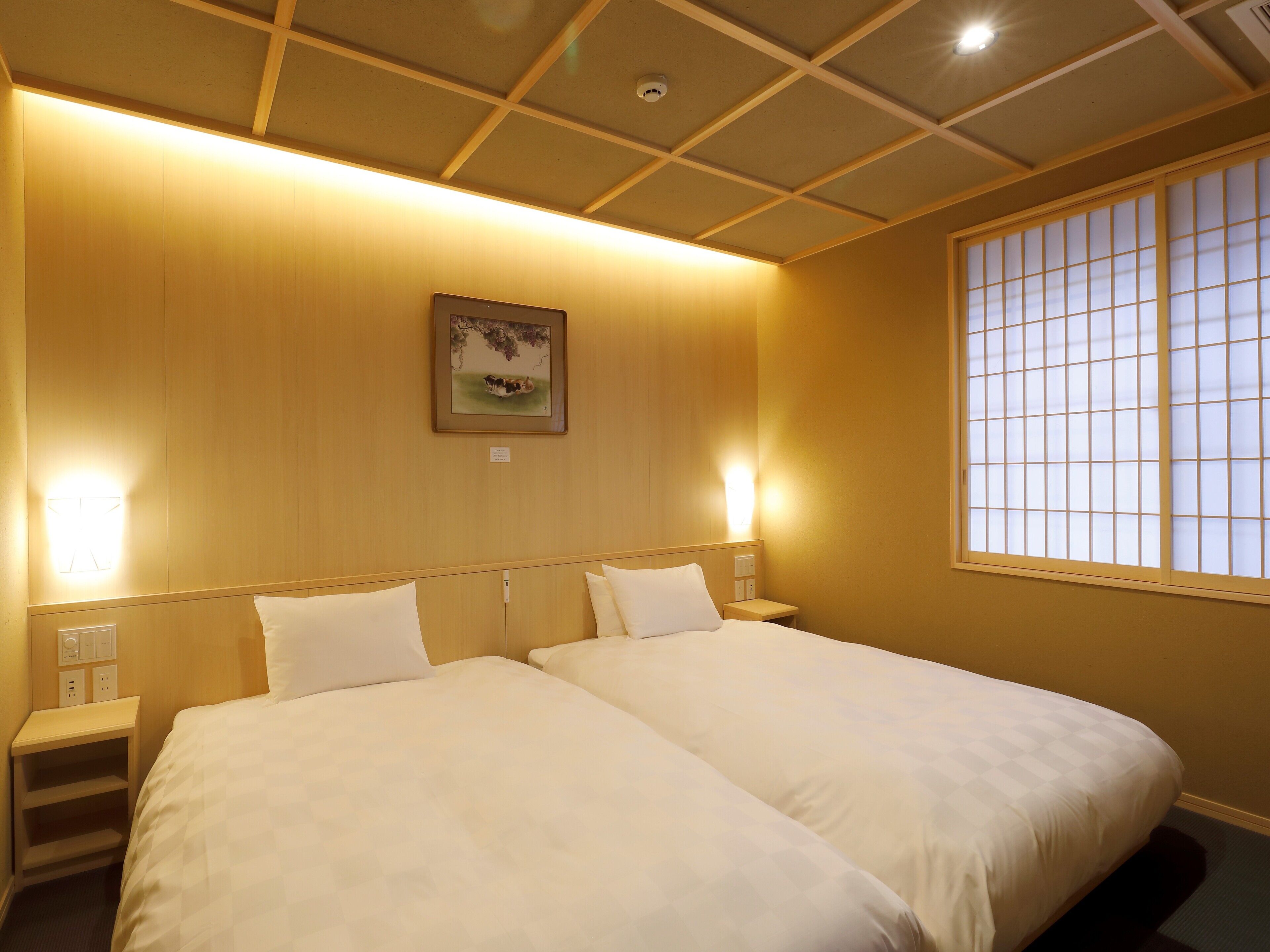 A hotel room with a large bed, two bedside tables, a nightstand, a wall-mounted picture, and a window with a view.