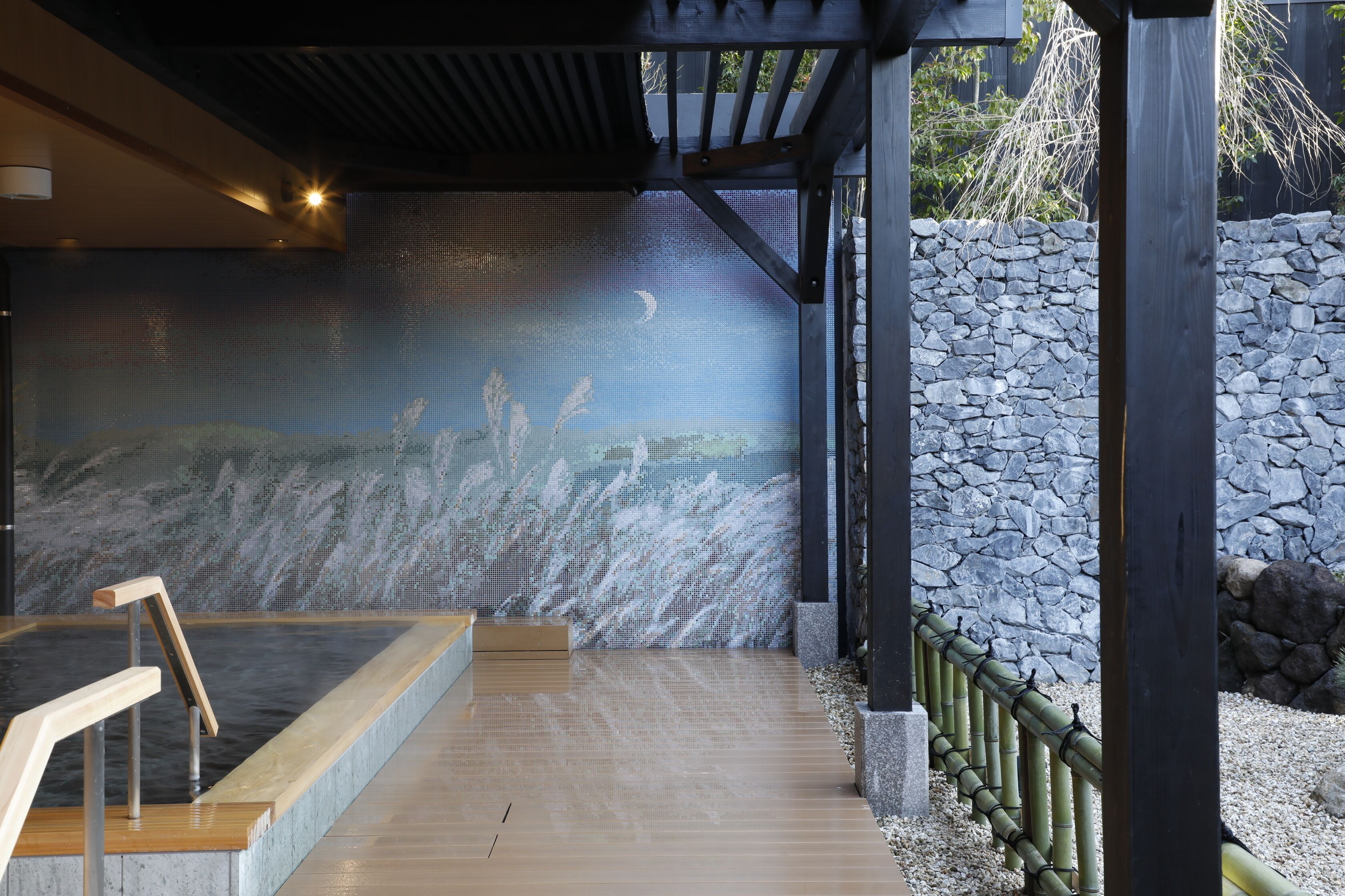 A spa area with a hot tub, a stone wall, and a wooden deck.