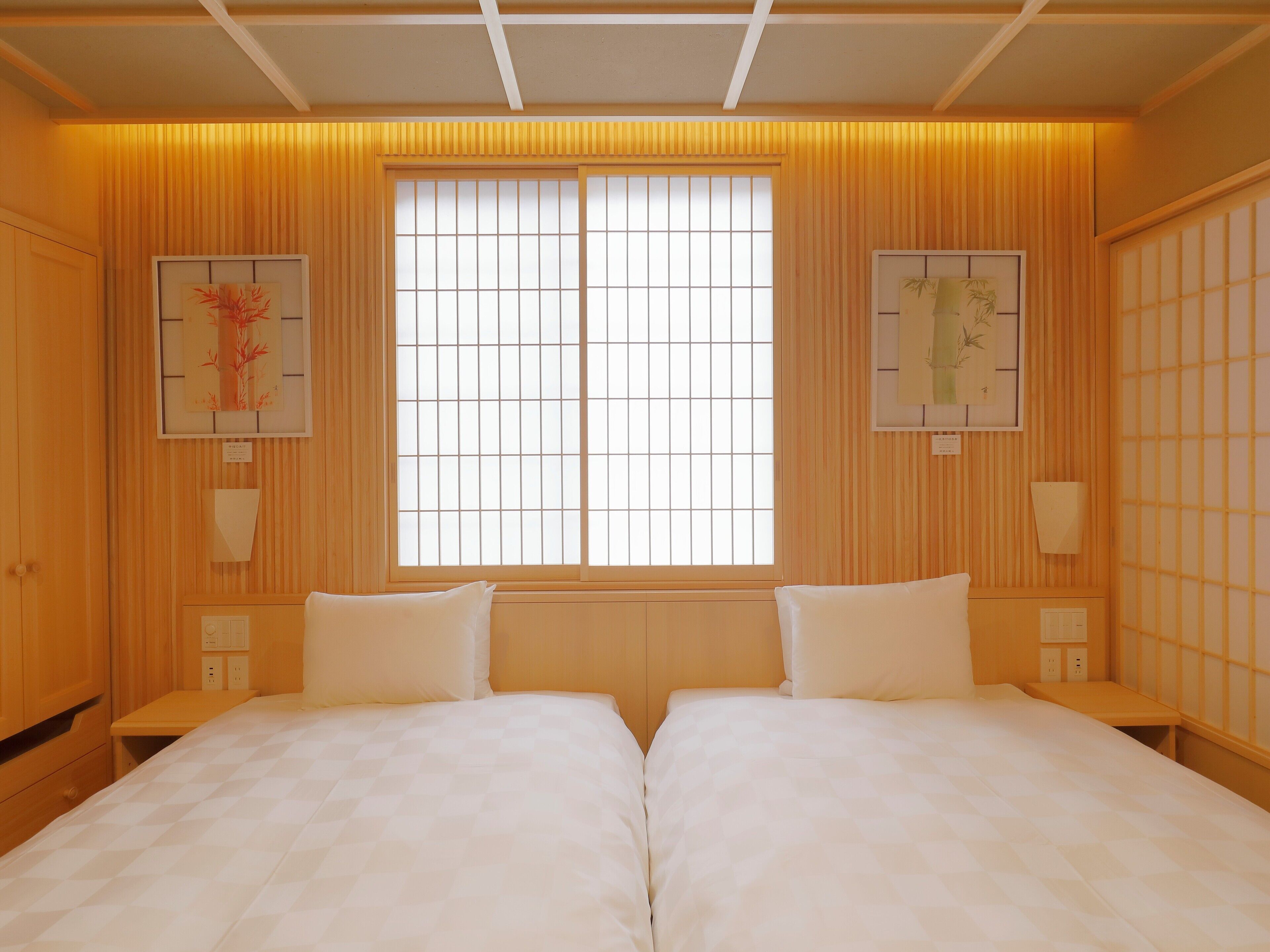 Habitación de hotel con una cama grande, dos mesitas de noche, un ventanal con diseño de cuadrícula y paneles de madera.