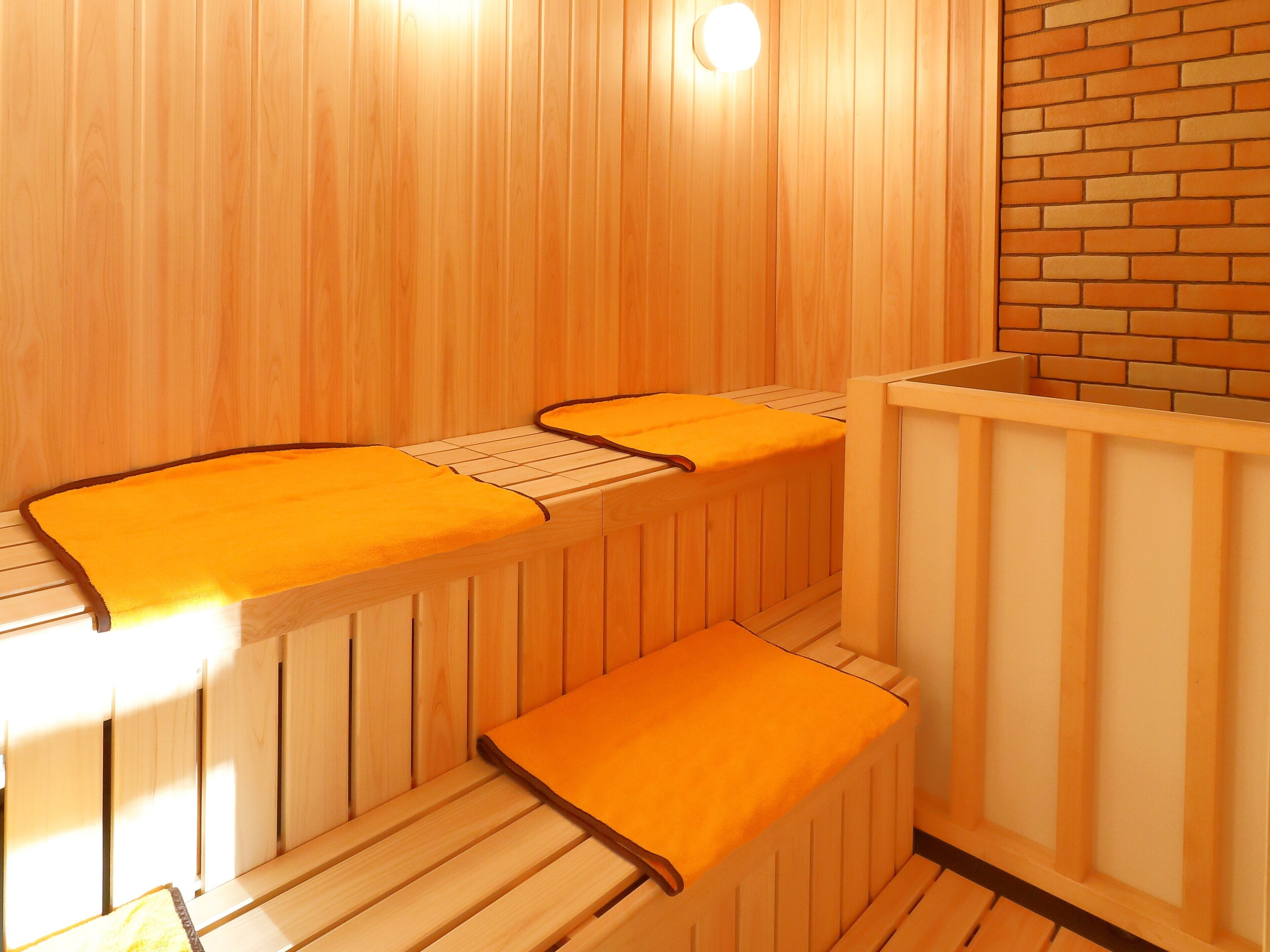 A sauna with wooden benches and benches with orange towels.