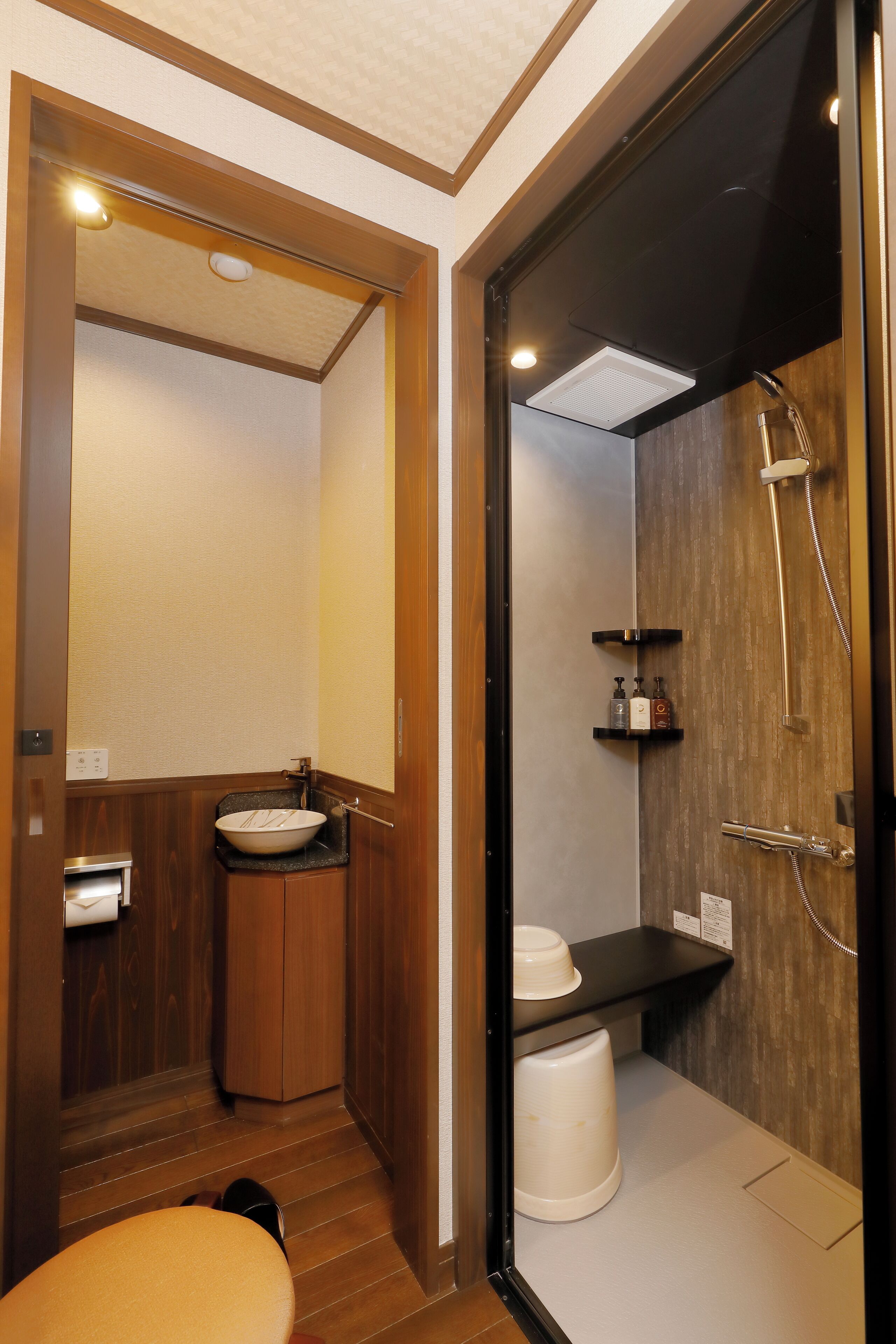 A compact bathroom with a wooden vanity, a sink, a toilet, and a shower area.