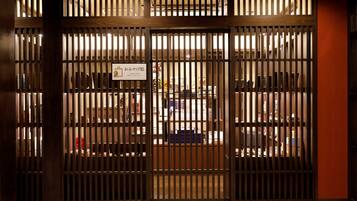 A traditional Japanese-style room with tatami flooring, a shoji screen door, and a view of a bookstore in the background.
