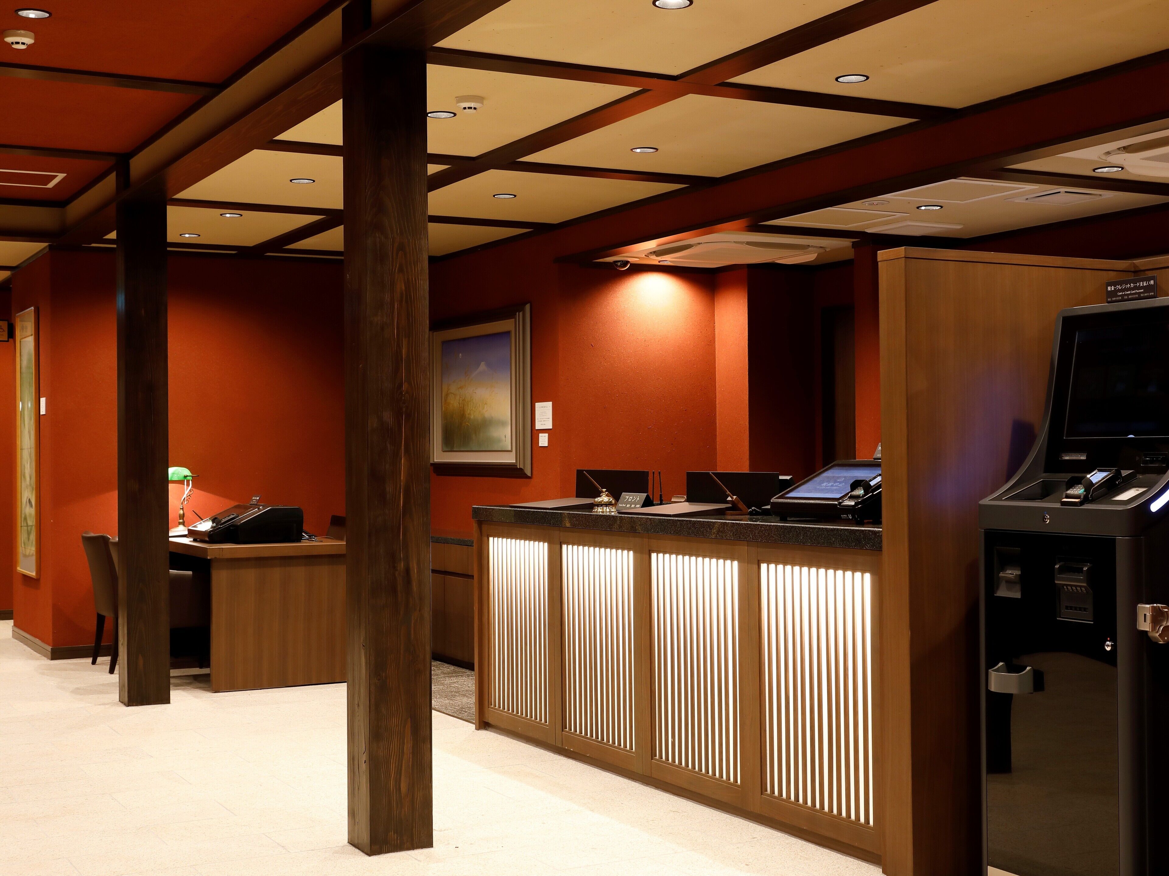 A hotel reception area with a wooden reception desk, a computer, and a cash register.