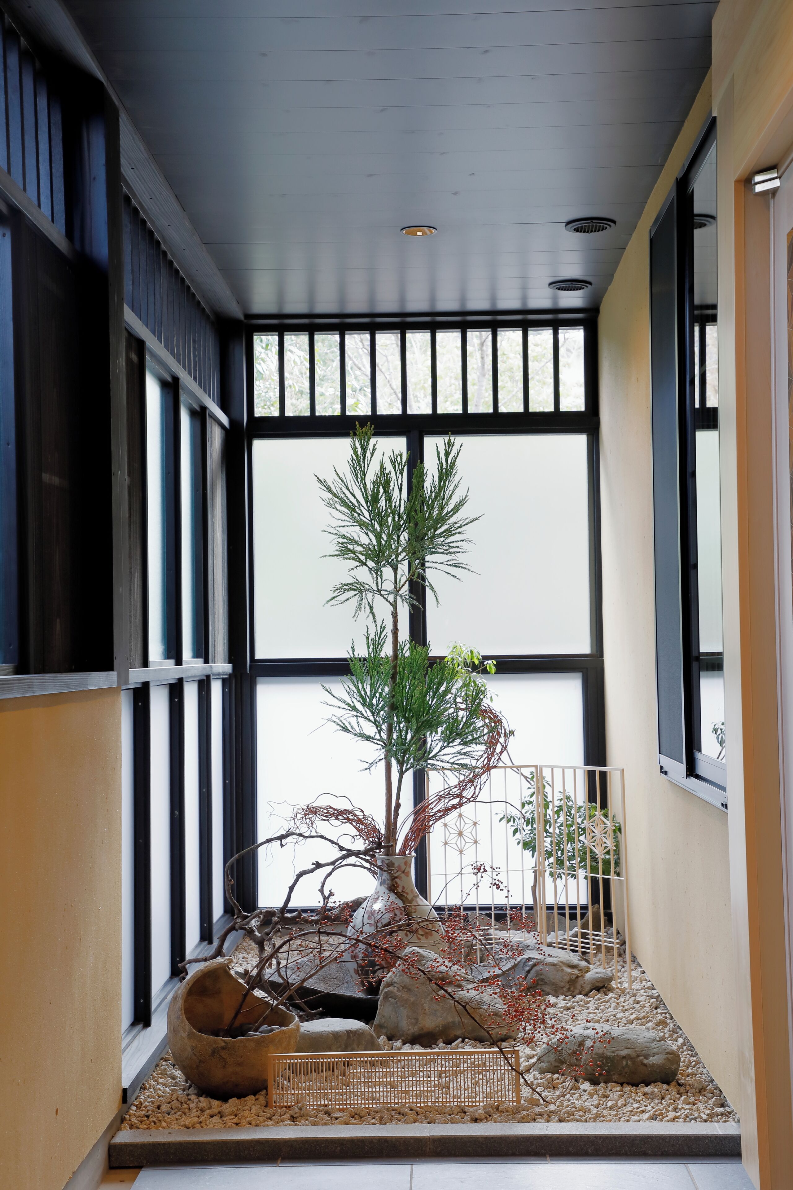A room with a large window, a potted plant, and a small table.