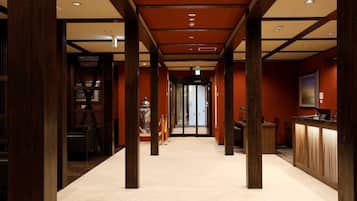 Un pasillo con pilares de madera, una recepción y una estantería.