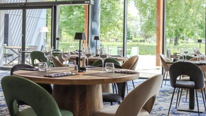 A restaurant with round tables, chairs, and wine glasses. - BEST OF BOTH (Divonne-les-Bains)