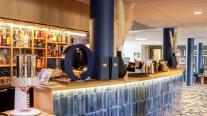 A bar area with a variety of liquor bottles, a coffee machine, and a circular mirror. - BEST OF BOTH (Divonne-les-Bains)