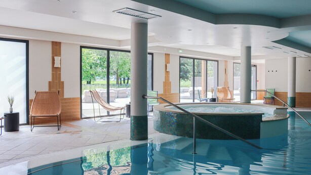 An indoor swimming pool with a hot tub, lounge chairs, and large windows offering a view of the outdoors. - BEST OF BOTH (Divonne-les-Bains)
