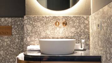 Un baño moderno con un espejo redondo, un lavabo blanco y una pared con textura.