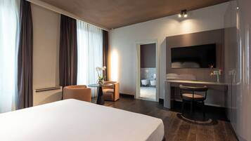 Relax in a spacious room with a large bed, a small table, and a comfortable chair.