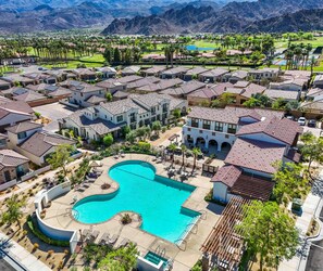 A residential area with a large swimming pool surrounded by houses with red-tiled roofs. - PGA210 2Bed PGA West, Pool & Hot Tub Steps Away! (La Quinta)