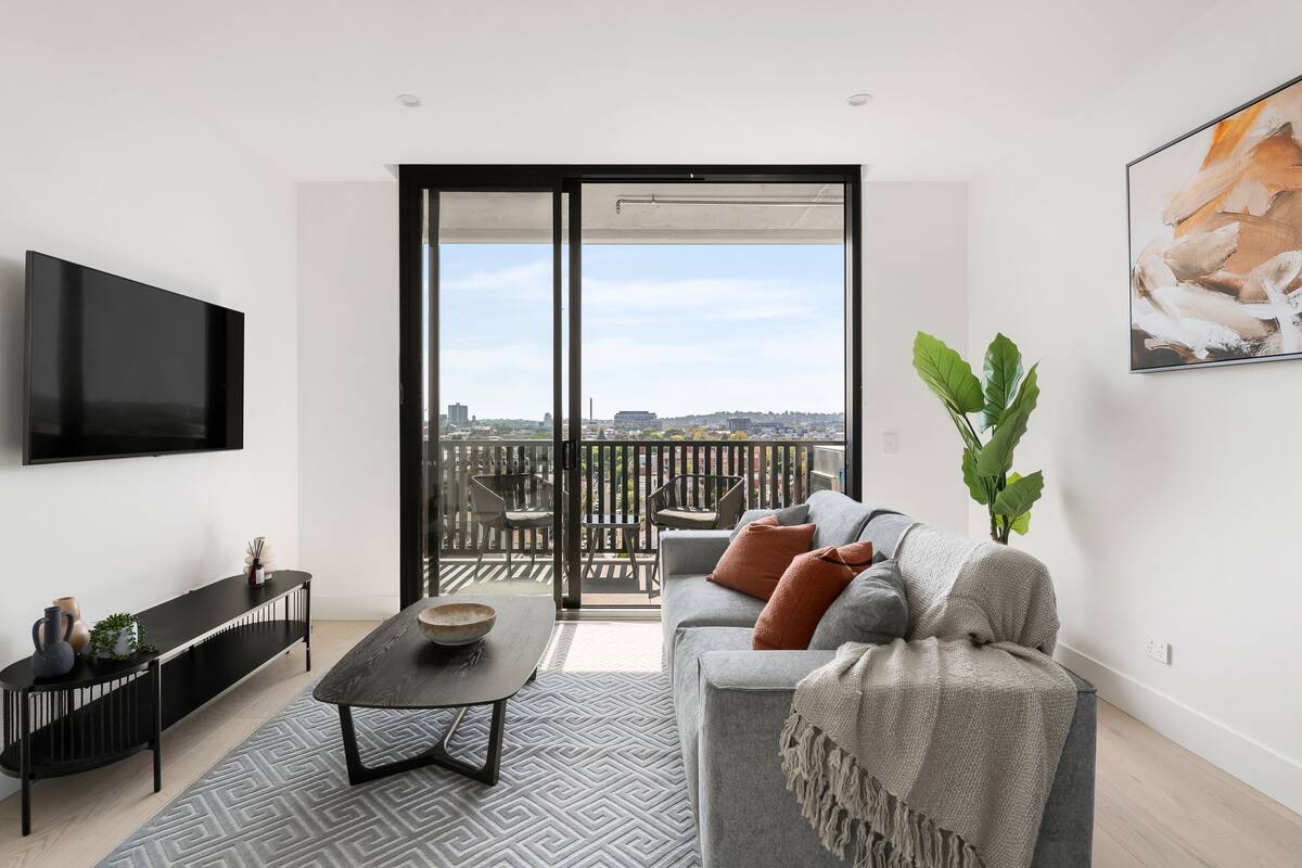 A modern living room with a sofa, a coffee table, and a TV mounted on the wall.