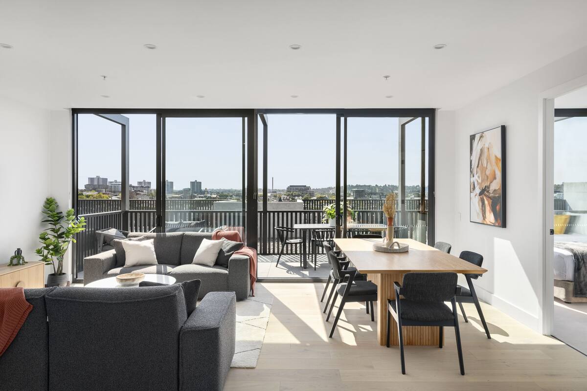 A modern living space with a balcony, large windows, and a dining area.