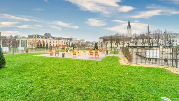 Un parc avec de l’herbe verte, des bancs et des jeux pour enfants.