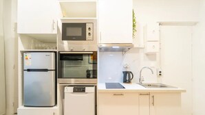 Une cuisine compacte équipée d’un réfrigérateur, d’un four à micro-ondes, d’un four, d’un lave-vaisselle et d’un évier.
