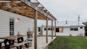 A wooden deck with a pergola, a rustic wooden table, and a bench. - Port Cottage on the Great Ocean Road (Port Campbell)