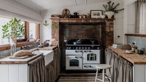 A kitchen with a brick fireplace, wooden countertops, and a stove. - Port Cottage on the Great Ocean Road (Port Campbell)
