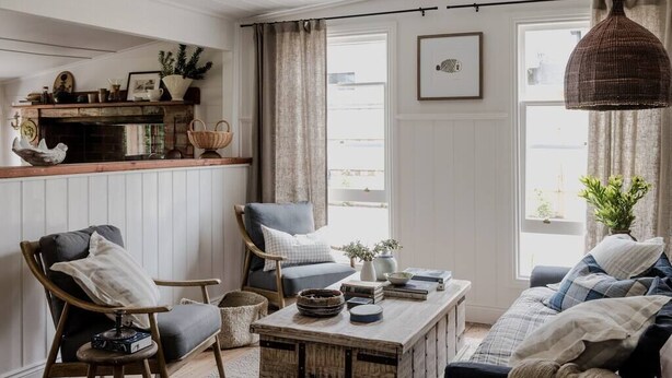 A cozy living room with a fireplace, a sofa, a coffee table, and a hanging light fixture. - Port Cottage on the Great Ocean Road (Port Campbell)