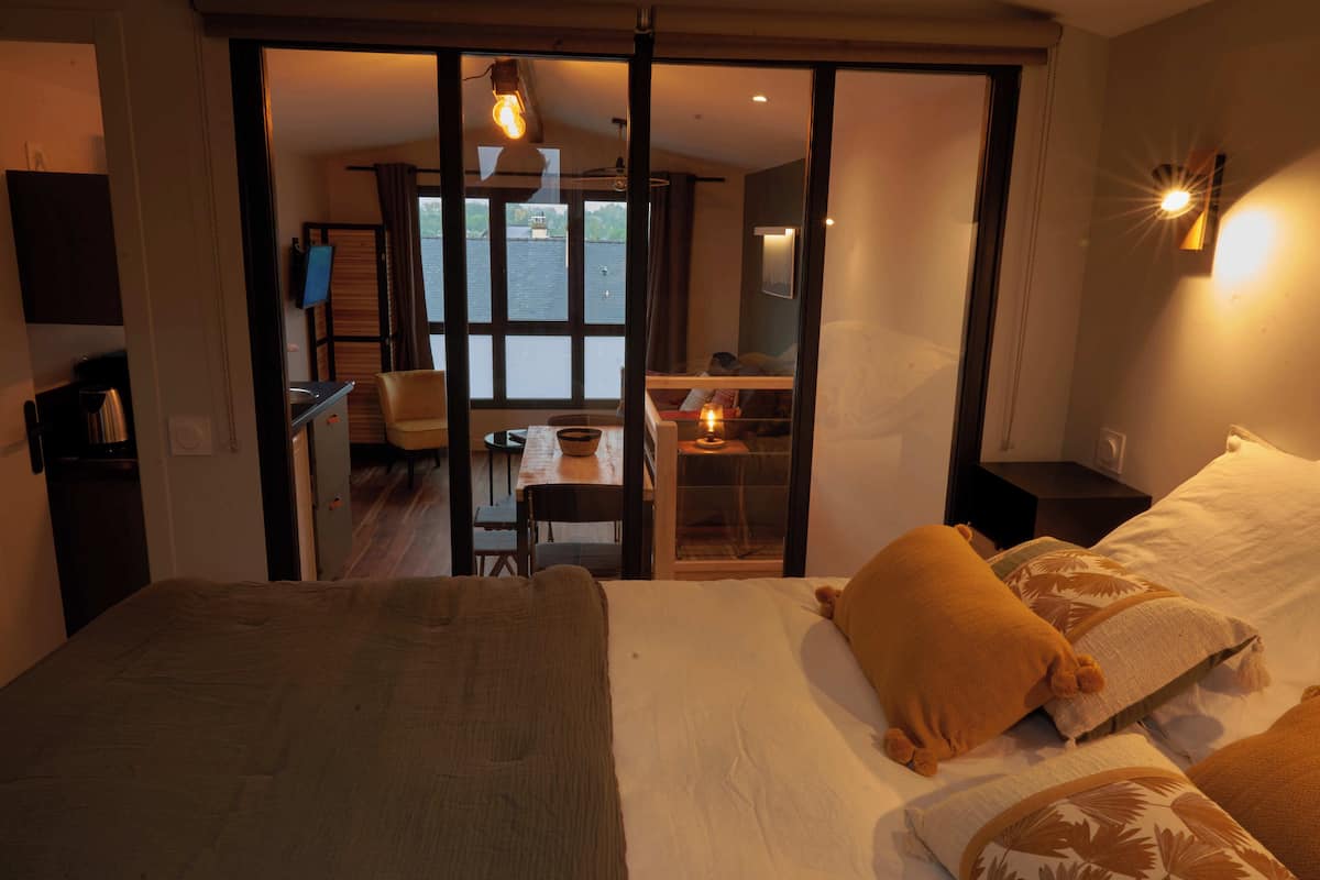 A bedroom with a large bed, a desk, and a view of a balcony.