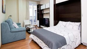 A hotel room with a bed, a sofa, a TV, and a balcony. - Madrid - Studio Gran via 1C (Madrid)