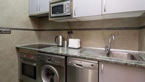 A compact kitchen with a microwave, oven, washing machine, and dishwasher. - Madrid - Studio Gran via 1C (Madrid)