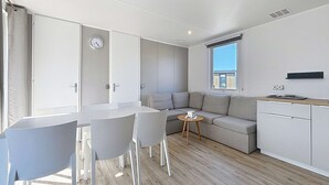 A modern kitchen with a dining area, a sofa, and a small table. - Luxury Mobile Home for 6, Heated Pool, 200m from Beach (Jullouville)