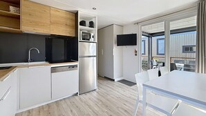 A modern kitchen with white cabinets, a stainless steel refrigerator, a microwave, and a flat-screen TV. - Luxury Mobile Home for 6, Heated Pool, 200m from Beach (Jullouville)