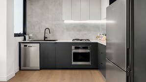 A modern kitchen with a dishwasher, oven, and built-in stove. - Fitzroy North Apartments by Urban Rest (Clifton Hill)